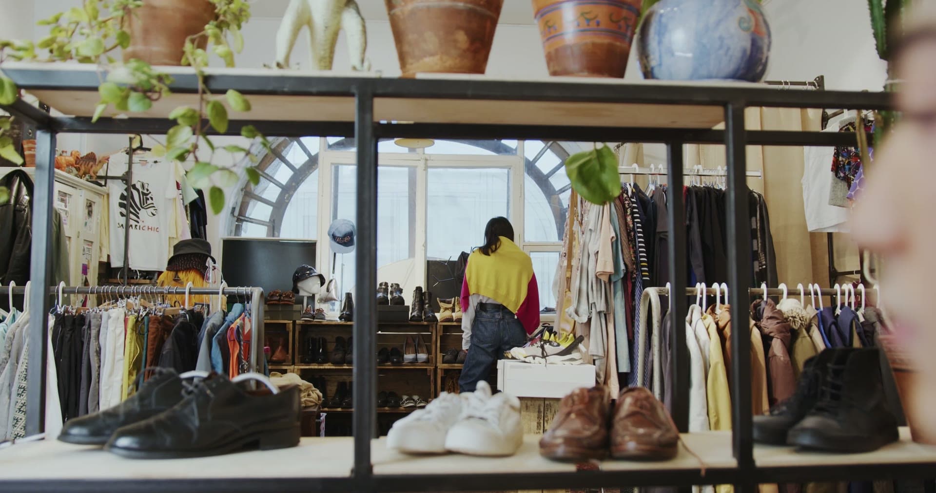 Inside the shop: racks of vintage clothing, boots and retro home goods under warm light